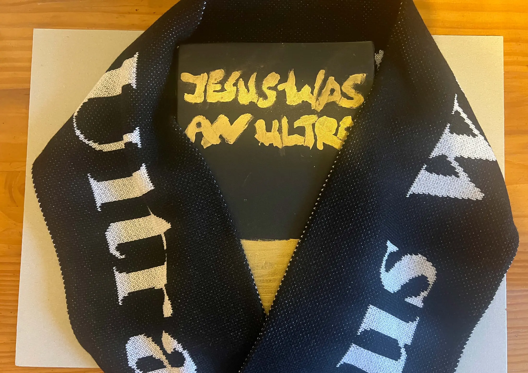 The finished book with a black and gold Jesus Was An Ultra scarf laid over it