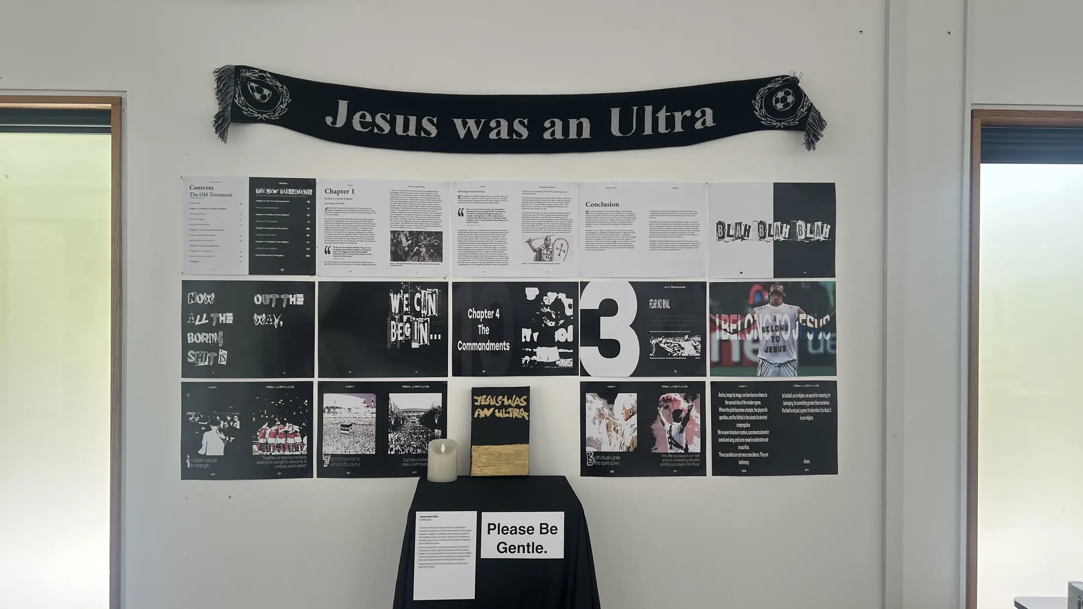 The degree show wall, a Jesus Was An Ultra scarf hung above printed spreads with the book on a stand